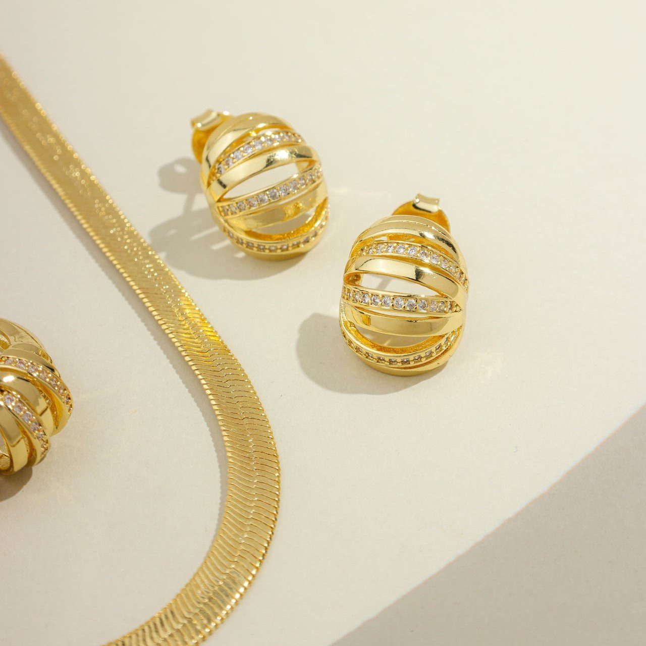 Brinco redondo com detalhes vazados e 3 listras com zircônias banhado a ouro 18k