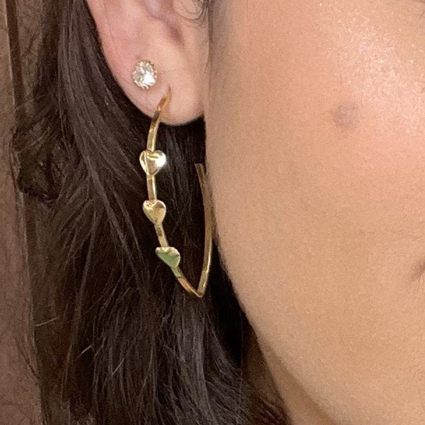 Brinco argola alongada com corações lisos banhado a ouro 18k